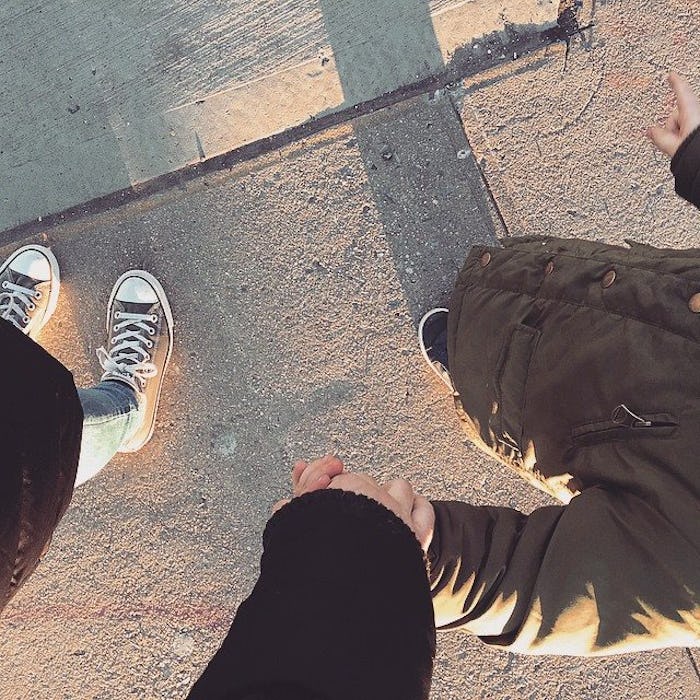 Young mom holding her kids hand while they are walking down the street