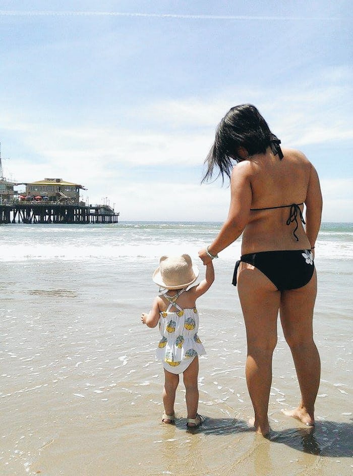 A mom holding her baby's hand while walking on the beach