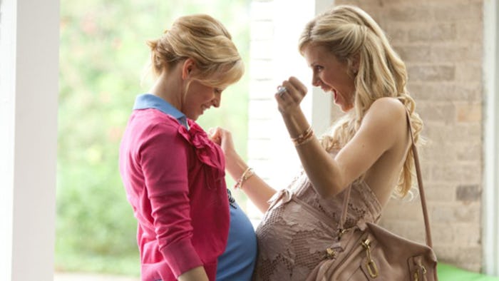 Two blonde pregnant moms rubbing their stomachs against each other and smiling
