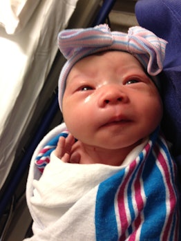 Lacey Vorrasi-Banis' newborn baby with a bow headband, wrapped in a blanket