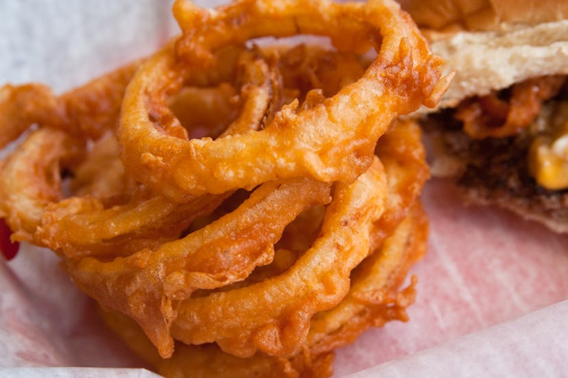 Fried onion rings served next to a burger