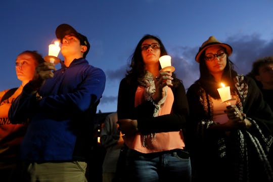 Four people standing with candles after the Paris attacks that strikes an emotional chord across the...