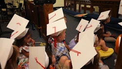 A group of preschool kids in Los Angeles wearing cardboard graduation caps