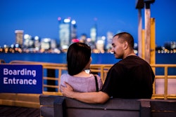 A man and a woman sitting on a bench near the harbor dock