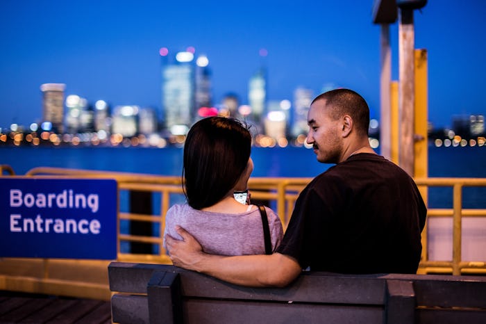 A man and a woman sitting on a bench near the harbor dock