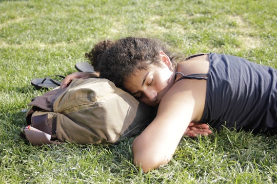 Woman lying on the ground using her bag as a pillow