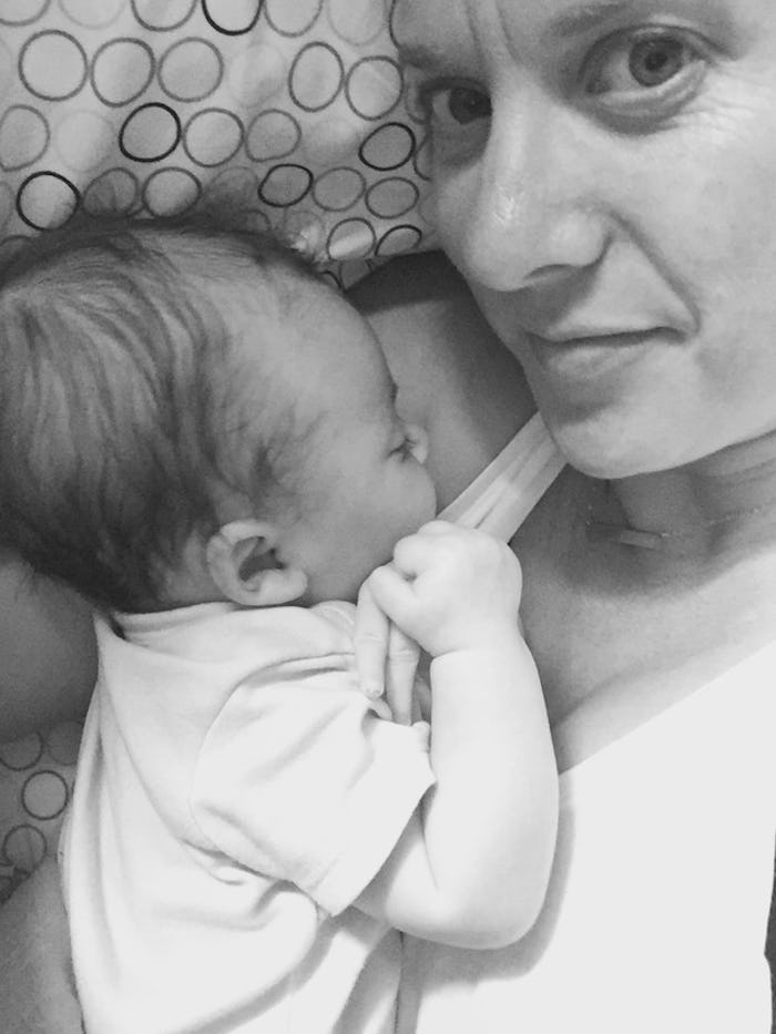 Rebekah Collins, who has postpartum anxiety in a selfie, lying in bed with her baby on her chest