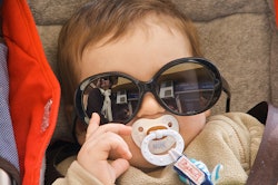 A badass baby posing with black sunglasses of its mother