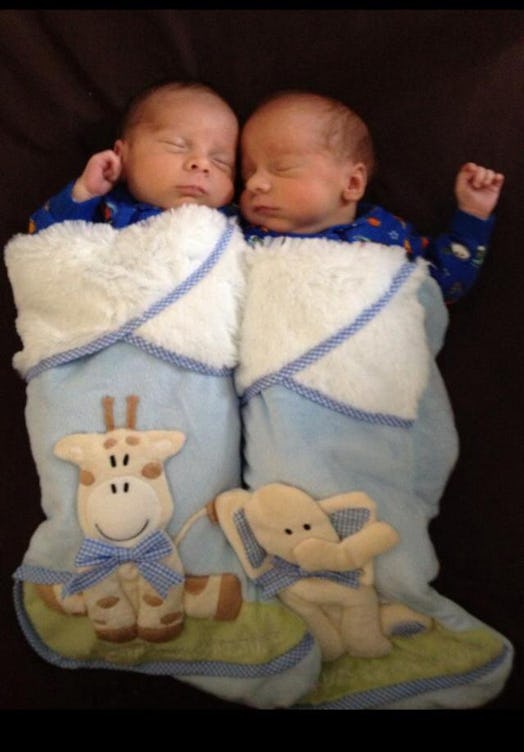 Newborn twins wrapped in blue matching blankets 
