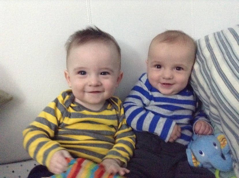 Twins wearing striped shirts sitting next to each other with toys in their hands