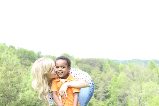 Woman hugging her autistic son while standing in front of a forrest