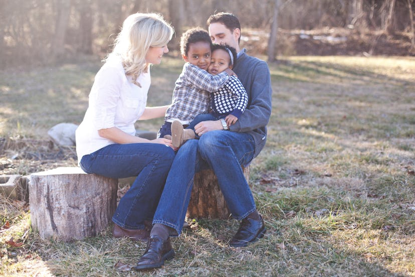 Happy family posing in the forest where parents are visibly happy, and their kids are hugging each o...