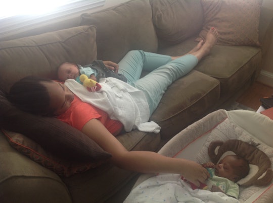 Tyrese Coleman lying on a couch with one of her babies while touching another in a crib beside her.