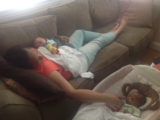 Tyrese Coleman lying on a couch with one of her babies while touching another in a crib beside her.