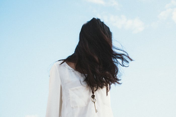 Woman standing outside on a windy day with her hair covering her face