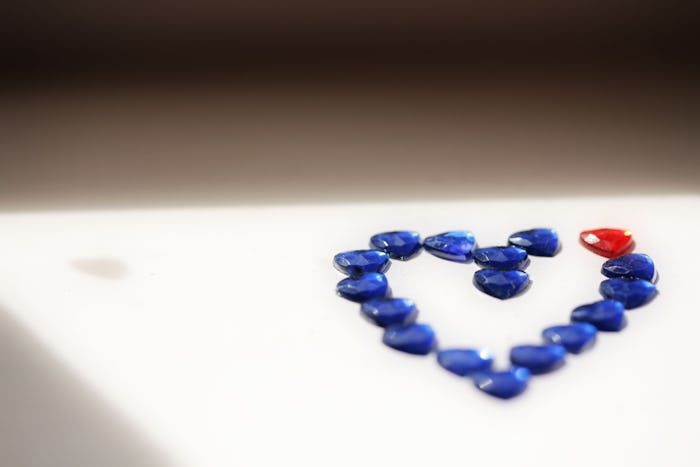 A sun-kissed heart shape made of blue and one red glass bead representing couples struggling to conc...