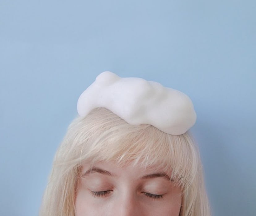 A blond girl standing in front of a blue wall with her eyes closed and shampoo on her head