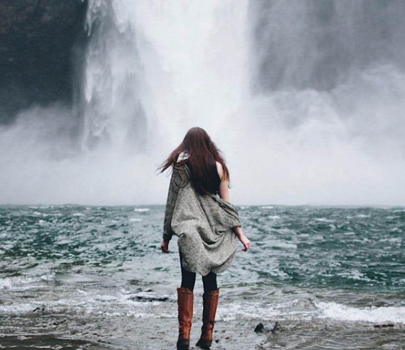 A girl photographed from her back in front of a waterfall