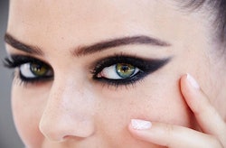 A woman posing with a black high school cat eye on her face 
