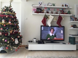 Christmas tree next to a television with a Christmas classic movie on display