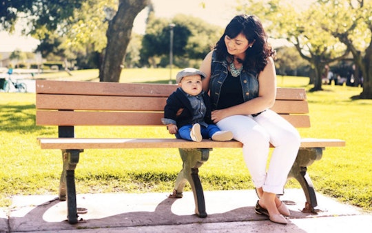 A divorced young woman sitting on a park bench next to her baby