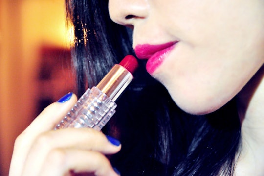 A woman putting lipstick on her lips