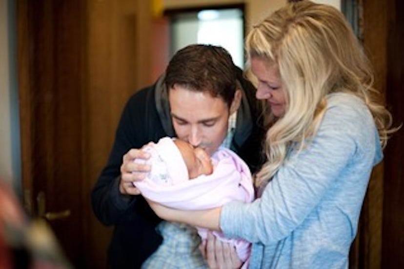 Lauren Casper's partner kissing a baby in her arms