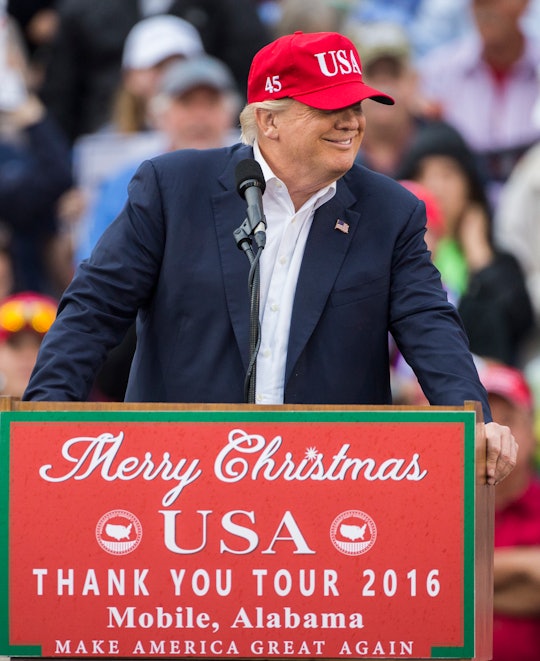 Donald Trump wearing a formal suit and a red cap during his speech