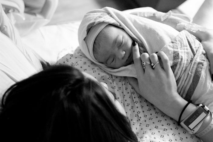 A mother cuddling her newborn baby while sleeping