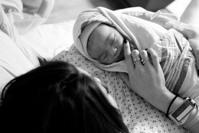 A mother cuddling her newborn baby while sleeping