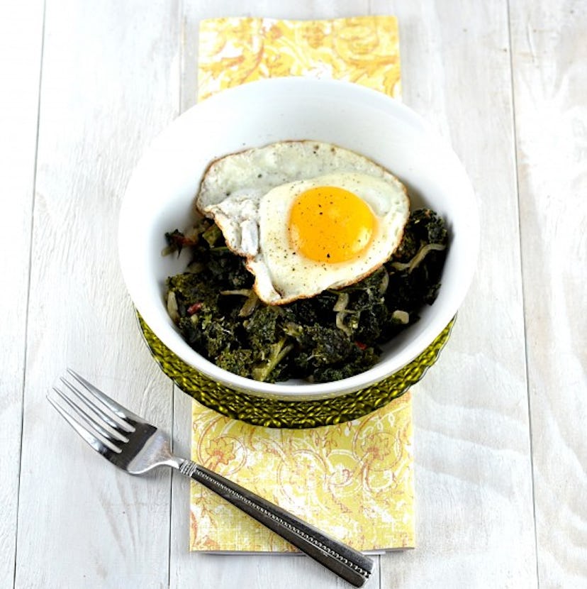 Spicy coconut braised kale served in a bowl with a baked egg