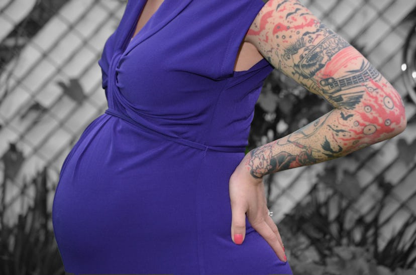 Tattooed pregnant woman posing in a blue dress