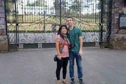A woman standing next to her partner in front of a large iron gate