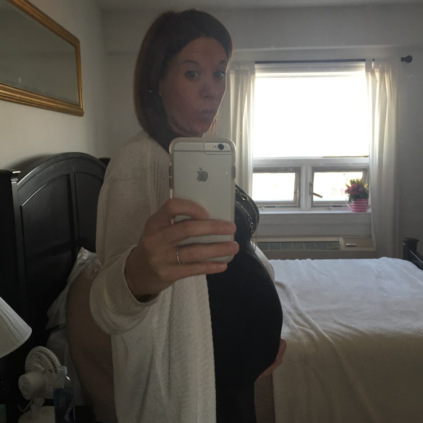 A pregnant woman taking a picture of herself in the mirror