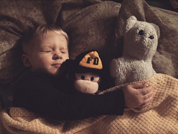 A little boy sleeping with two stuffed toys