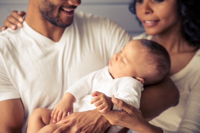 A dad holding his baby and the mom caressing the baby