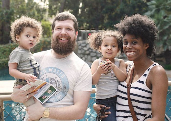 A couple posing while holding their two kids with their hands