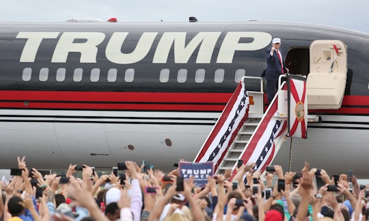 Donald Trump in front of his Boeing 757 private jet with a "Trump" logo on it, waving to his support...