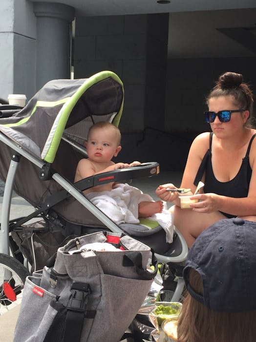 A mother giving food to her baby that's sitting in trolley