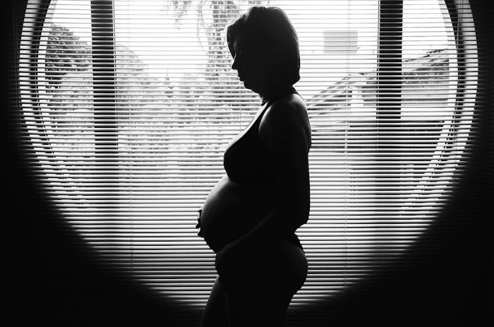 A side-view of a pregnant woman who is scared of late-term abortions