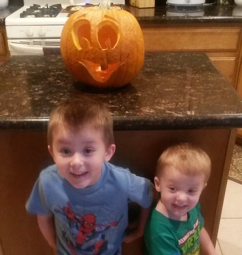 Christi Cazins' two sons are standing in front of a pumpkin lantern