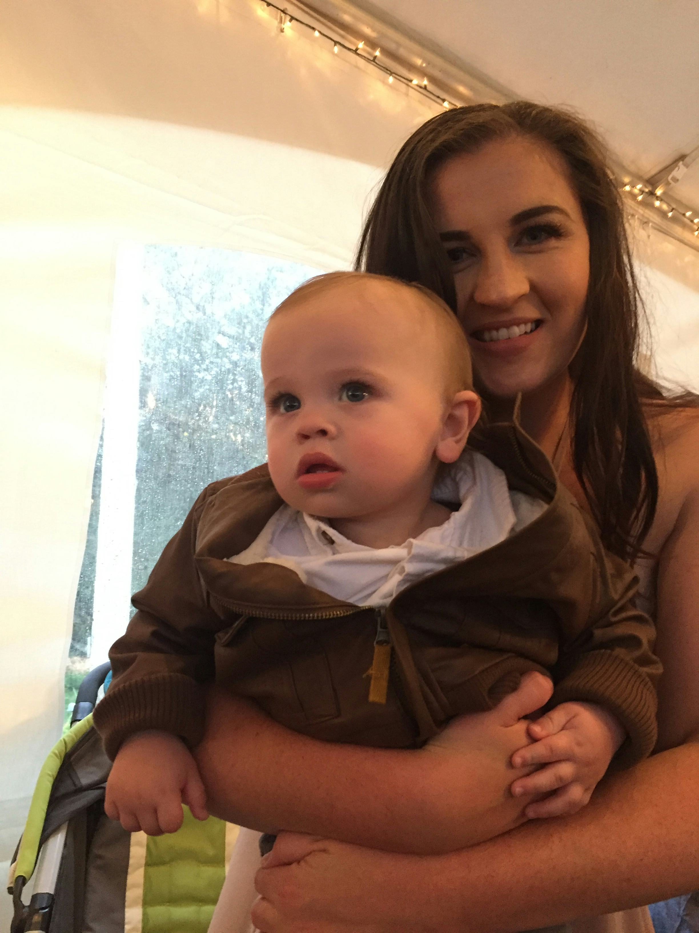 Haley Depass, who has experienced Postpartum hair loss, smiling while holding her baby