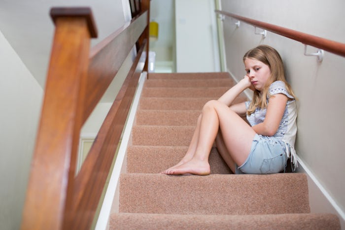 An angry looking girl with a Sensory Processing Disorder sitting on the stairs