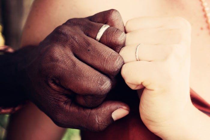 Millennial Parents' with their hands and ring fingers touching.