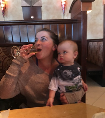 Mom drinking wine in a restaurant while her baby is sitting in her lap