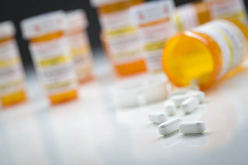 A shot of blurred medication bottles with focused meds spilled on a surface.
