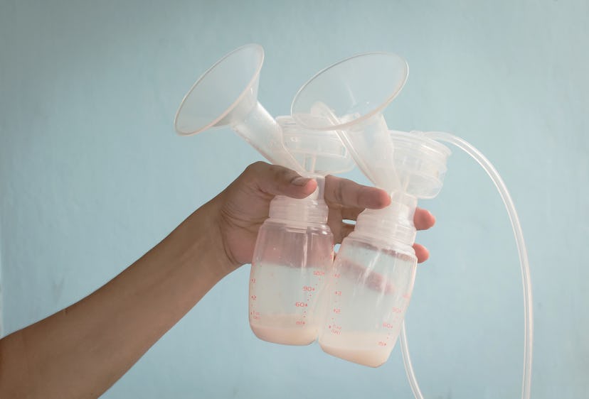  A hand is holding 2 breast pumps.