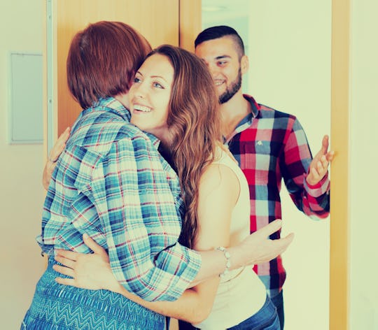 A woman hugging her mother in law while her husband is standing behind her.