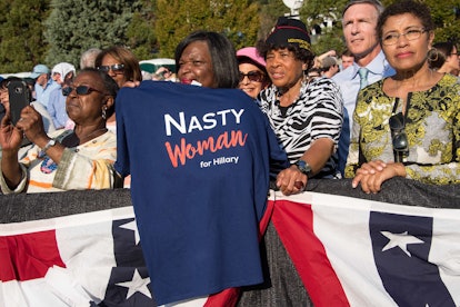 A woman holding a shirt with a "nasty woman for Hillary" text sign