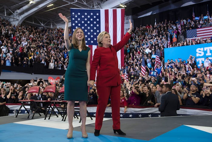 Chelsea and Hillary Clinton waving to the crowd with the flag of the U.S. behind them